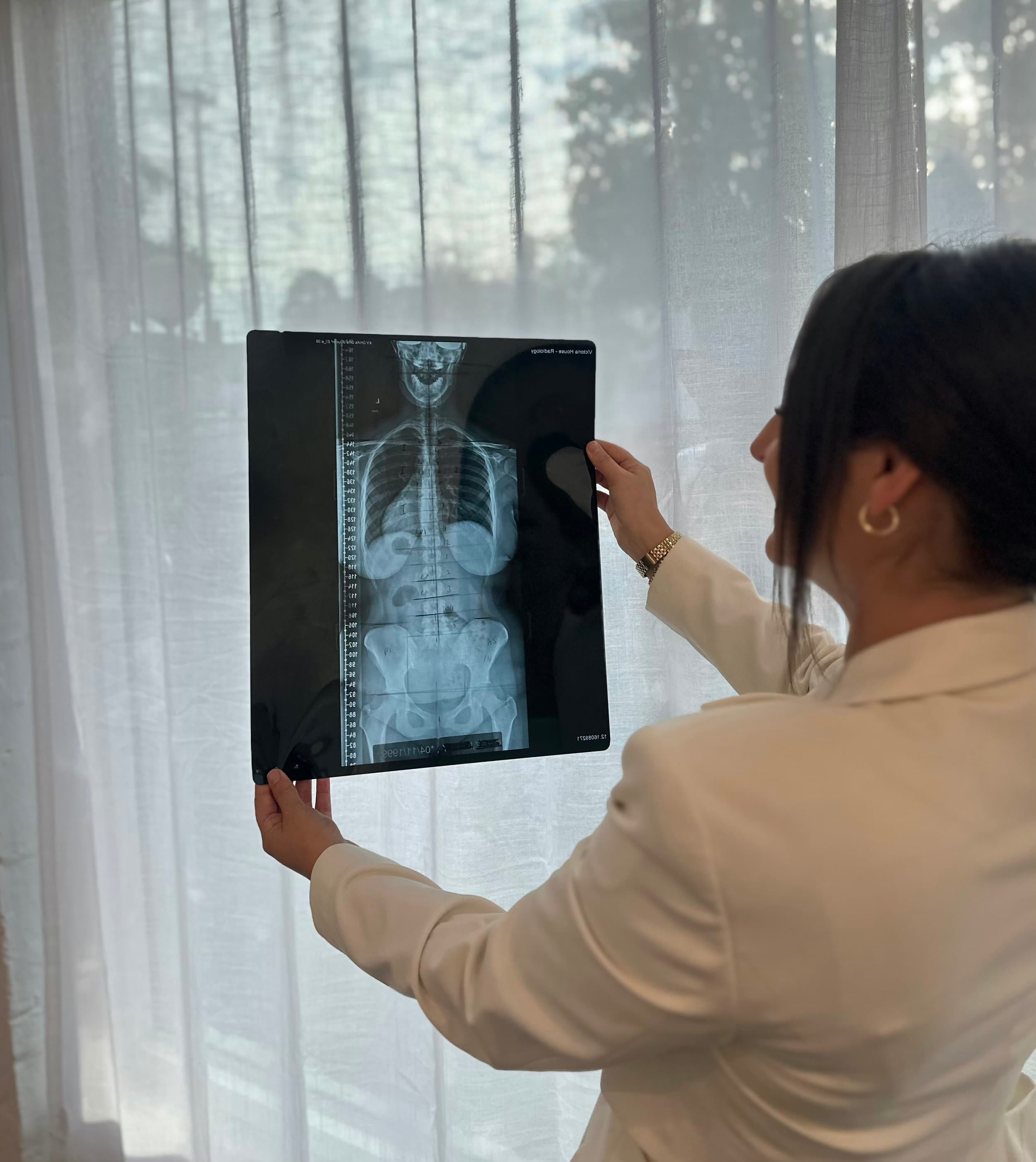 Dr Asena seated at a desk with chiropractic education materials